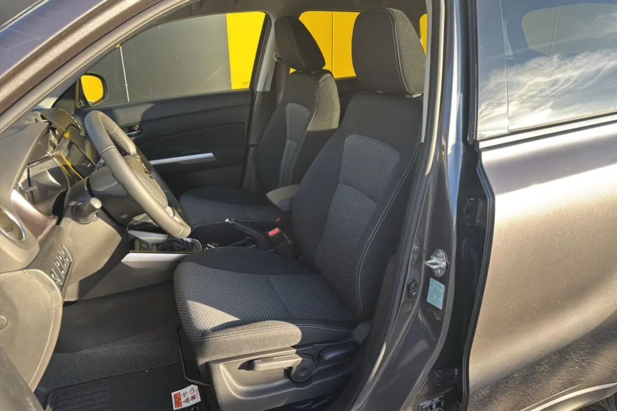Intérieur avant droit du Suzuki Vitara Hybrid 110 Privilege Allgrip 2025 en Titan dark gray, sièges tissu noir et volant multifonctions.