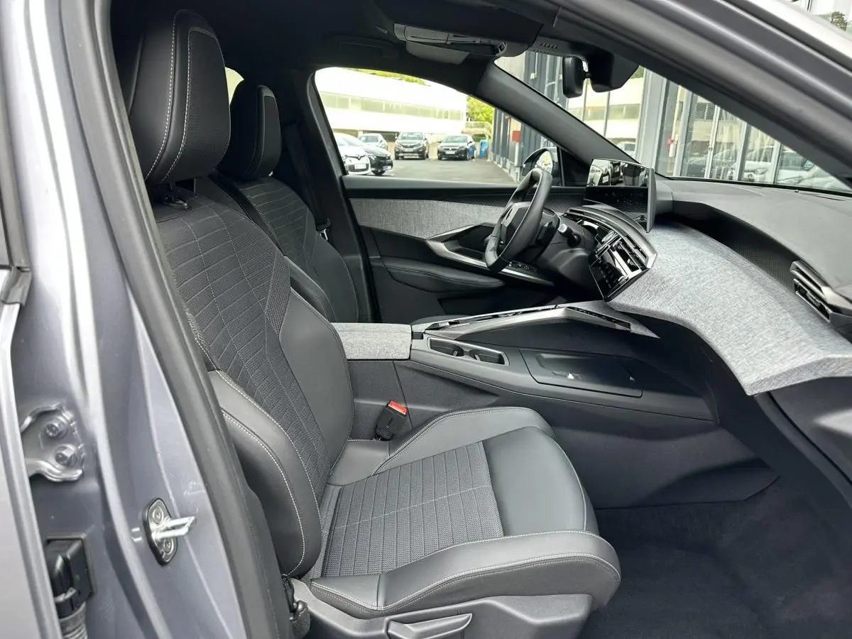 Vue intérieure côté conducteur du Peugeot 3008 gris Artense 2024, mettant en valeur les sièges tissu et cuir et le tableau de bord moderne.