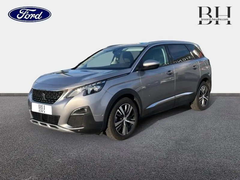 Peugeot 5008 gris Artense en 3/4 avant droit, mettant en valeur ses jantes alu et son design moderne.