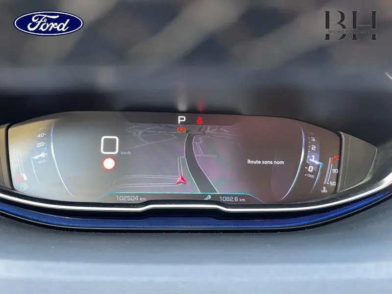 Tableau de bord numérique de Peugeot 5008 gris Artense, affichage de navigation et compteurs en vue frontale rapprochée.