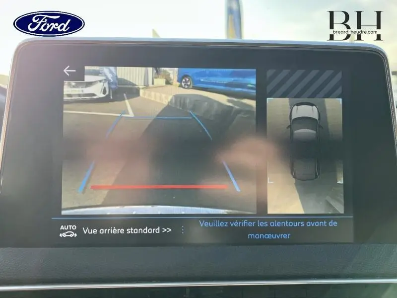 Écran de caméra de recul montrant l’arrière d’un Peugeot 5008 gris Artense avec lignes de guidage bleues et rouges.