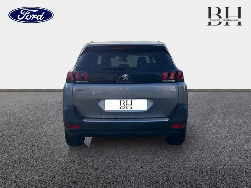 Vue arrière d'un Peugeot 5008 gris Artense avec feux LED caractéristiques et hayon fermé sur fond neutre.
