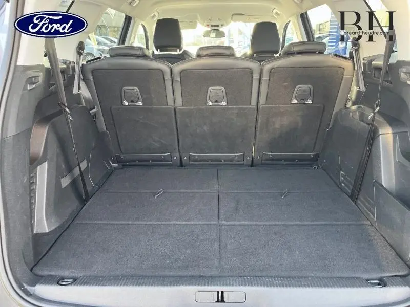 Vue arrière du coffre spacieux avec sièges arrière noirs relevés d'un SUV gris, montrant la capacité modulable du véhicule.