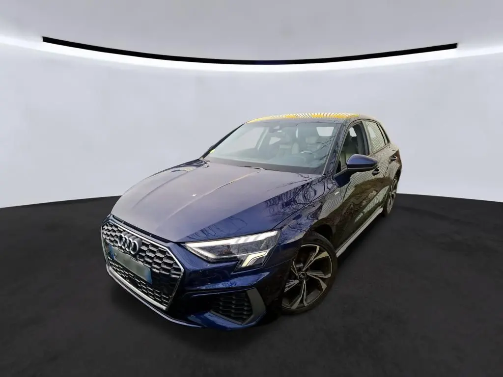 Audi A3 2.0 TDI S-Line bleu vue 3/4 avant droit dans un showroom avec mur en bois et enseigne lumineuse.