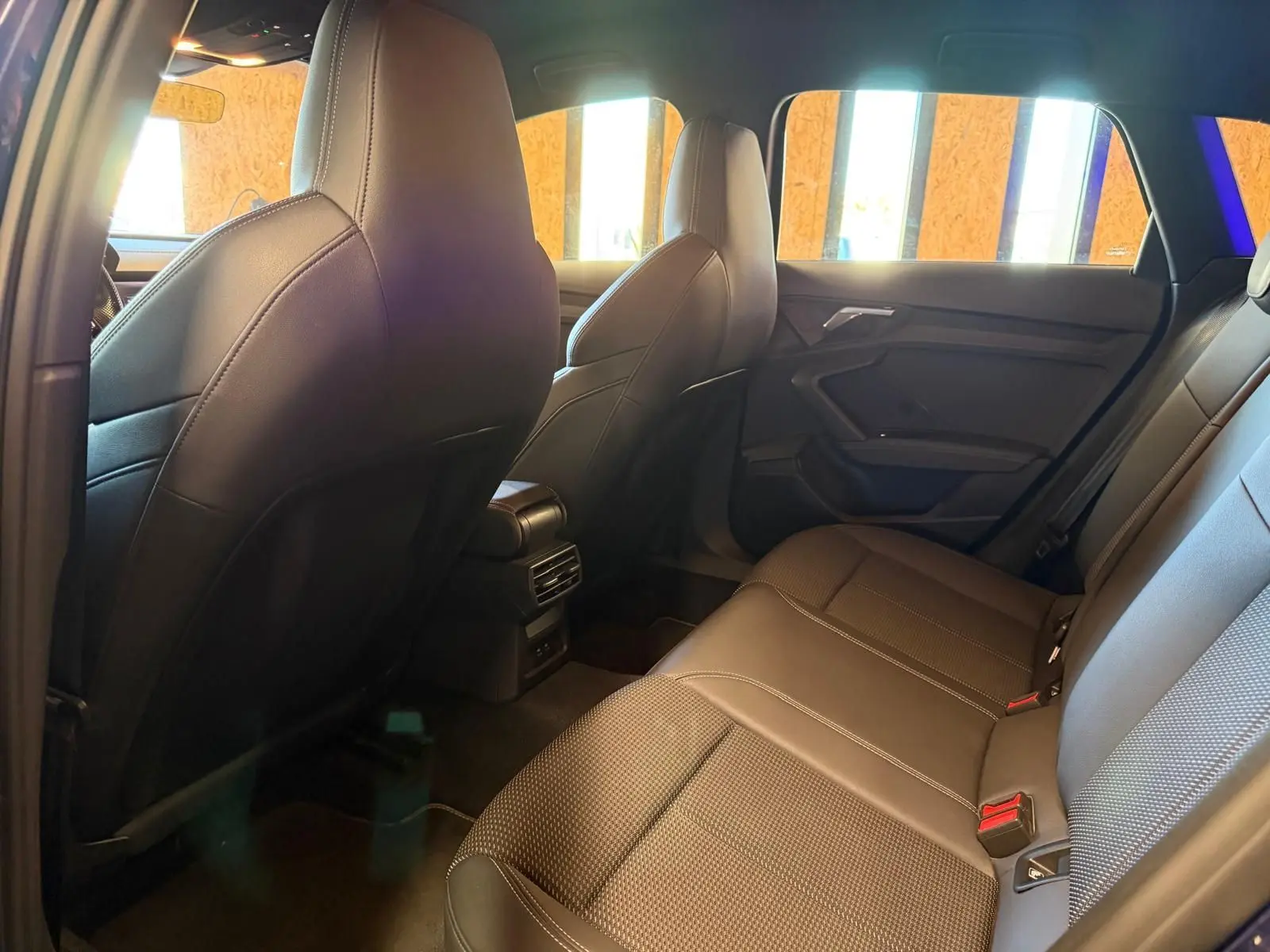 Vue intérieure arrière de l'Audi A3 2.0 TDI 150 S-Tronic S-Line 2022, sièges en tissu noir et habillage de porte sombre.