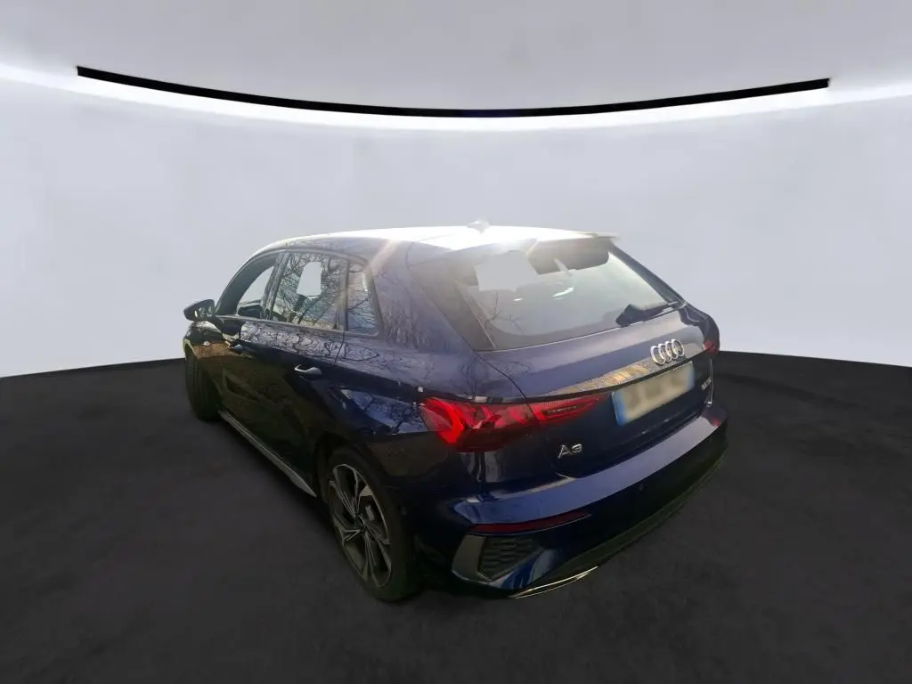 Vue frontale d'une Audi A3 2.0 TDI S-Line bleu foncé avec calandre hexagonale et logo Audi visible en intérieur.