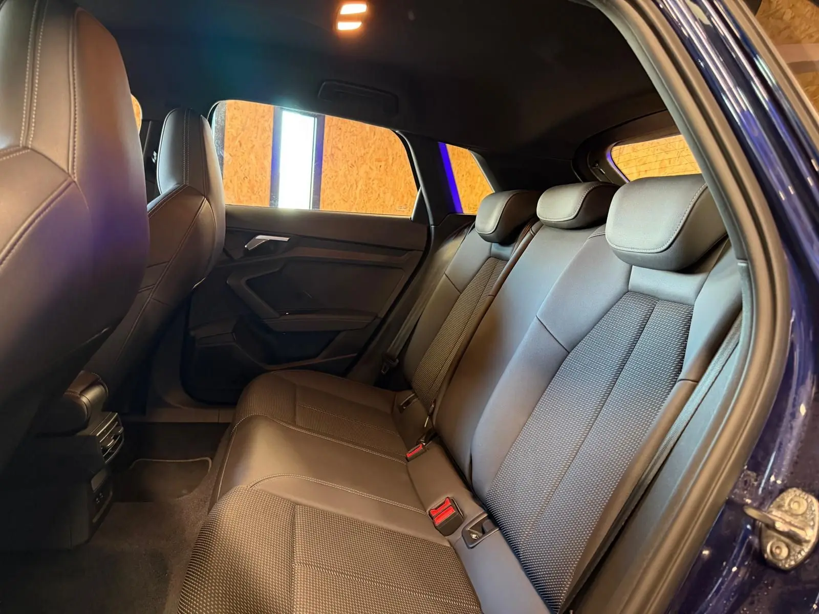 Vue intérieure côté droit des sièges arrière en tissu noir d'une Audi A3 2.0 TDI S-Line bleu 2022 avec porte ouverte.