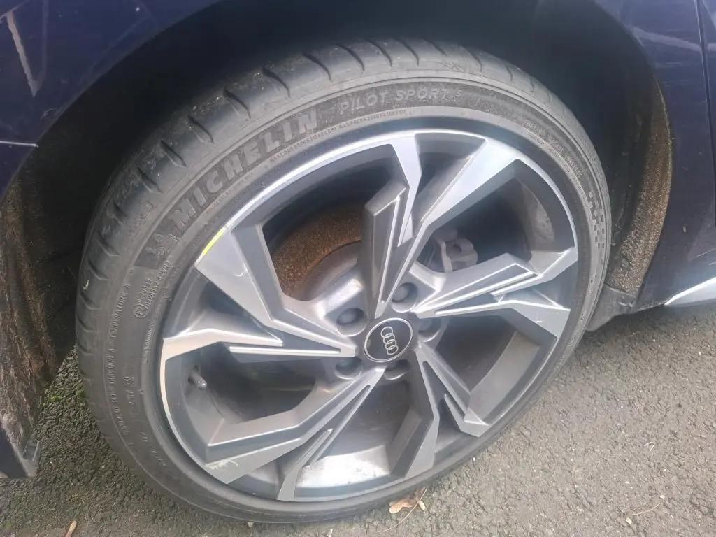 Gros plan sur la roue avant gauche d'une Audi A3 bleu 2022 avec jante alliage au design moderne.