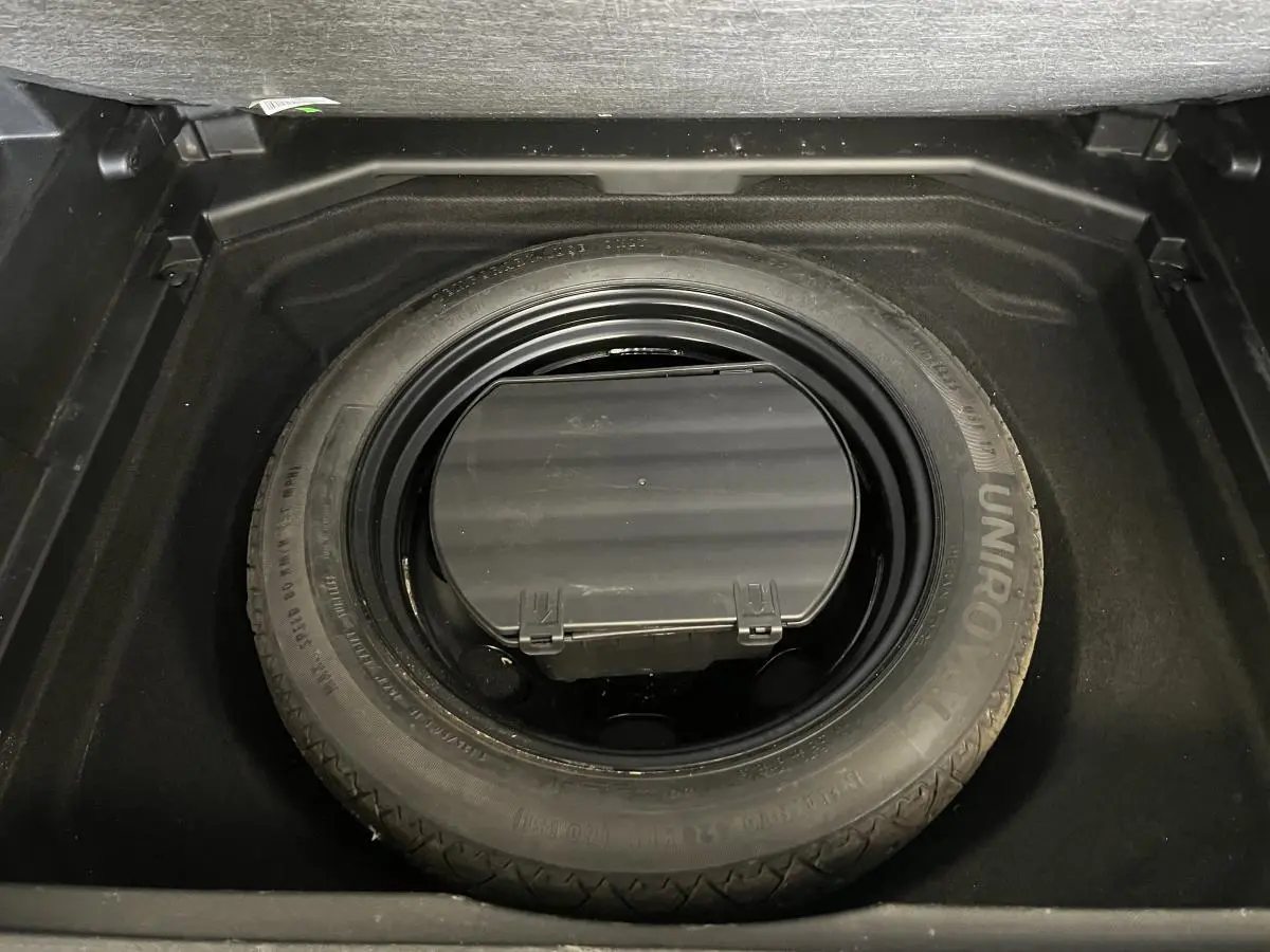 Gros plan sur la roue de secours type galette dans le coffre du Peugeot 3008 Diesel bleu 2022.