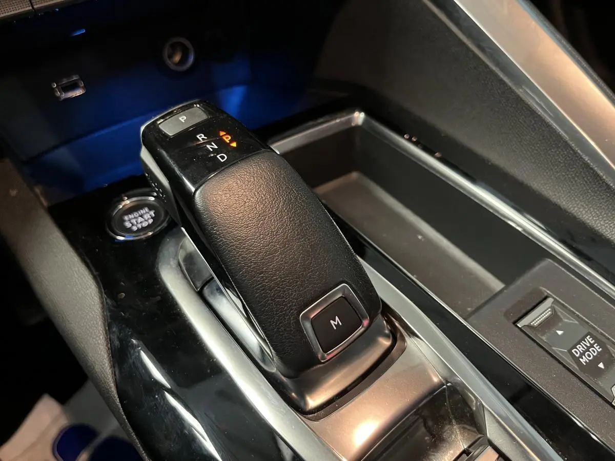 Le levier de vitesse automatique noir du Peugeot 3008 2022 avec bouton mode manuel, entouré de la console brillante.