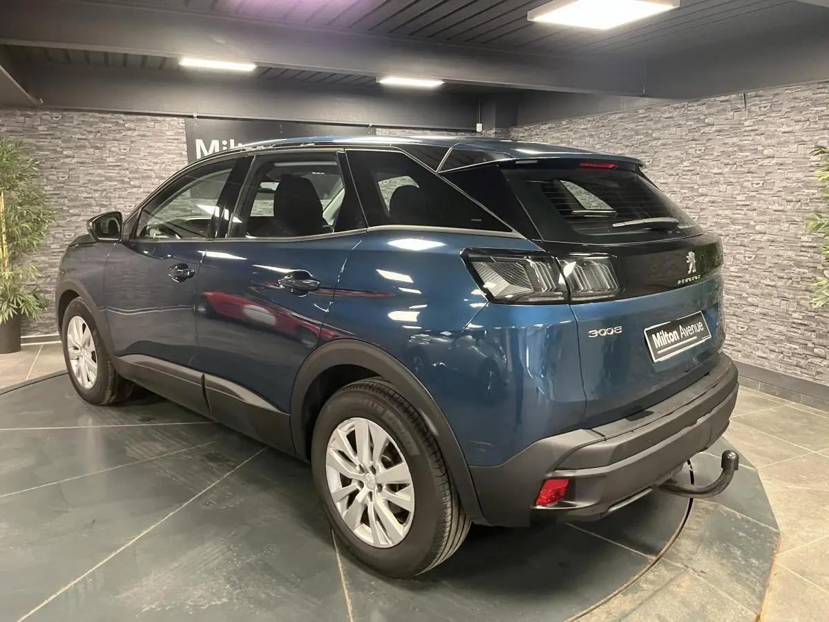 Peugeot 3008 bleu 3/4 arrière droit avec attelage démontable et jantes alliage 17 pouces dans un showroom.