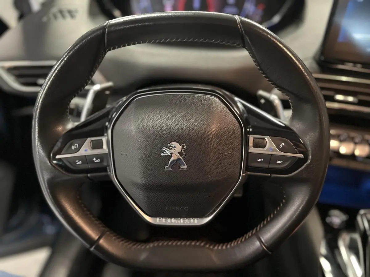 Volant compact en cuir noir du Peugeot 3008 2022 avec commandes intégrées et logo lion central chromé.