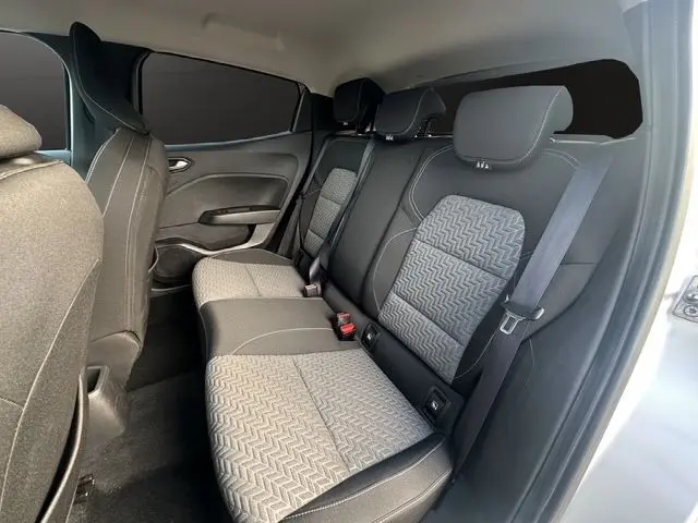 Vue latérale droite de l'intérieur arrière de la Renault Clio V TCE 90 Evolution, sièges tissu gris noir avec vitres arrière surteintées.