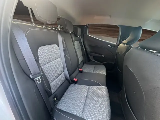 Vue intérieure arrière droite de la Renault Clio V TCE 90 Evolution 2023, sièges tissu gris noir avec ceinture de sécurité.