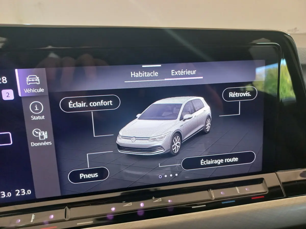 Écran tactile affichant une Volkswagen Golf blanche en vue 3/4 avant avec options éclairage et pneus détaillées.