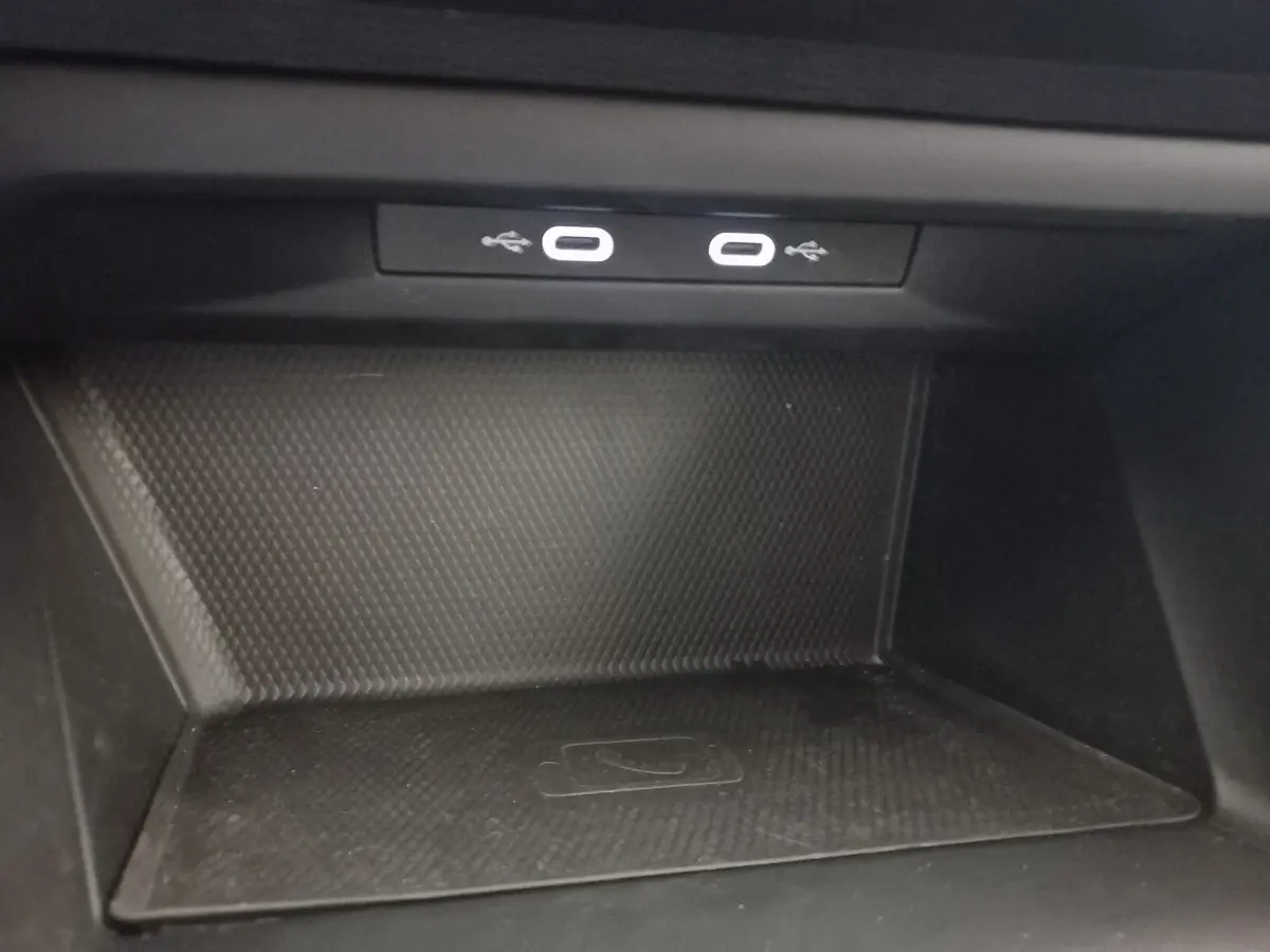 Gros plan sur la zone de recharge sans fil et ports USB du Volkswagen Golf 1.5 bleu, intérieur noir.