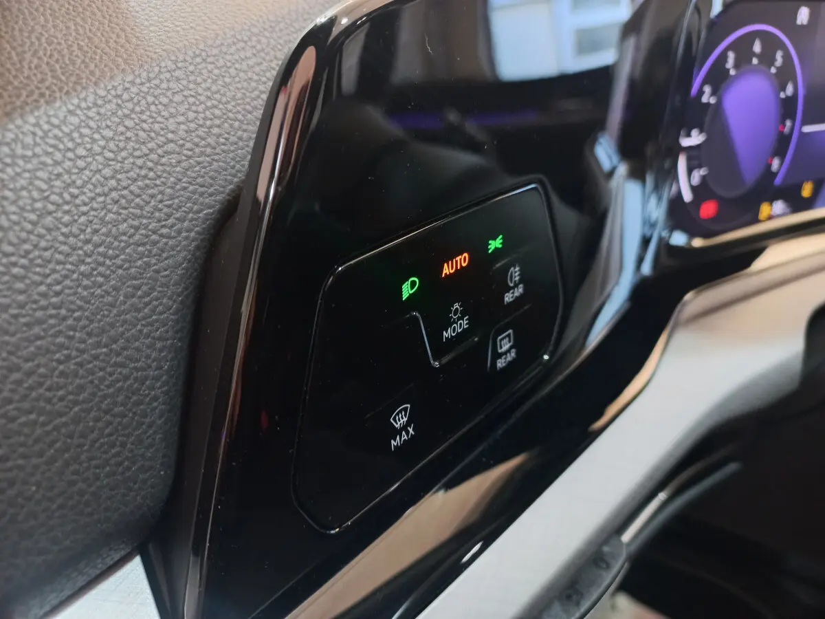 Détail du tableau de bord noir brillant de la Volkswagen Golf 2022, avec commandes d'éclairage et affichage digital.