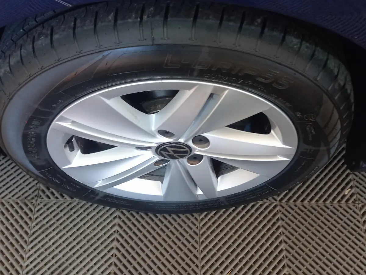 Gros plan sur la roue avant droite d'une Volkswagen Golf bleu, jante alliage argentée avec logo VW central.