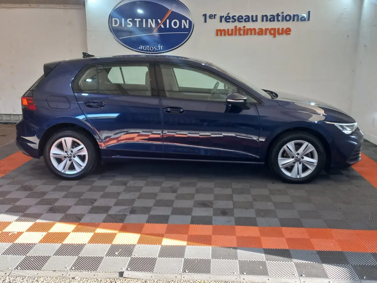 Profil droit d'une Volkswagen Golf bleu 2022, avec jantes alliage et éclairage LED avant visible.