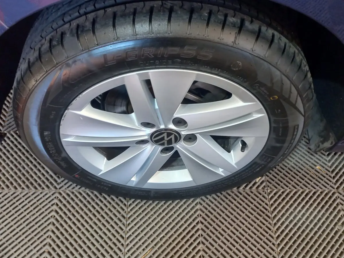 Gros plan sur la roue avant droite d'une Volkswagen Golf bleue, jante alliage argentée avec logo VW central.