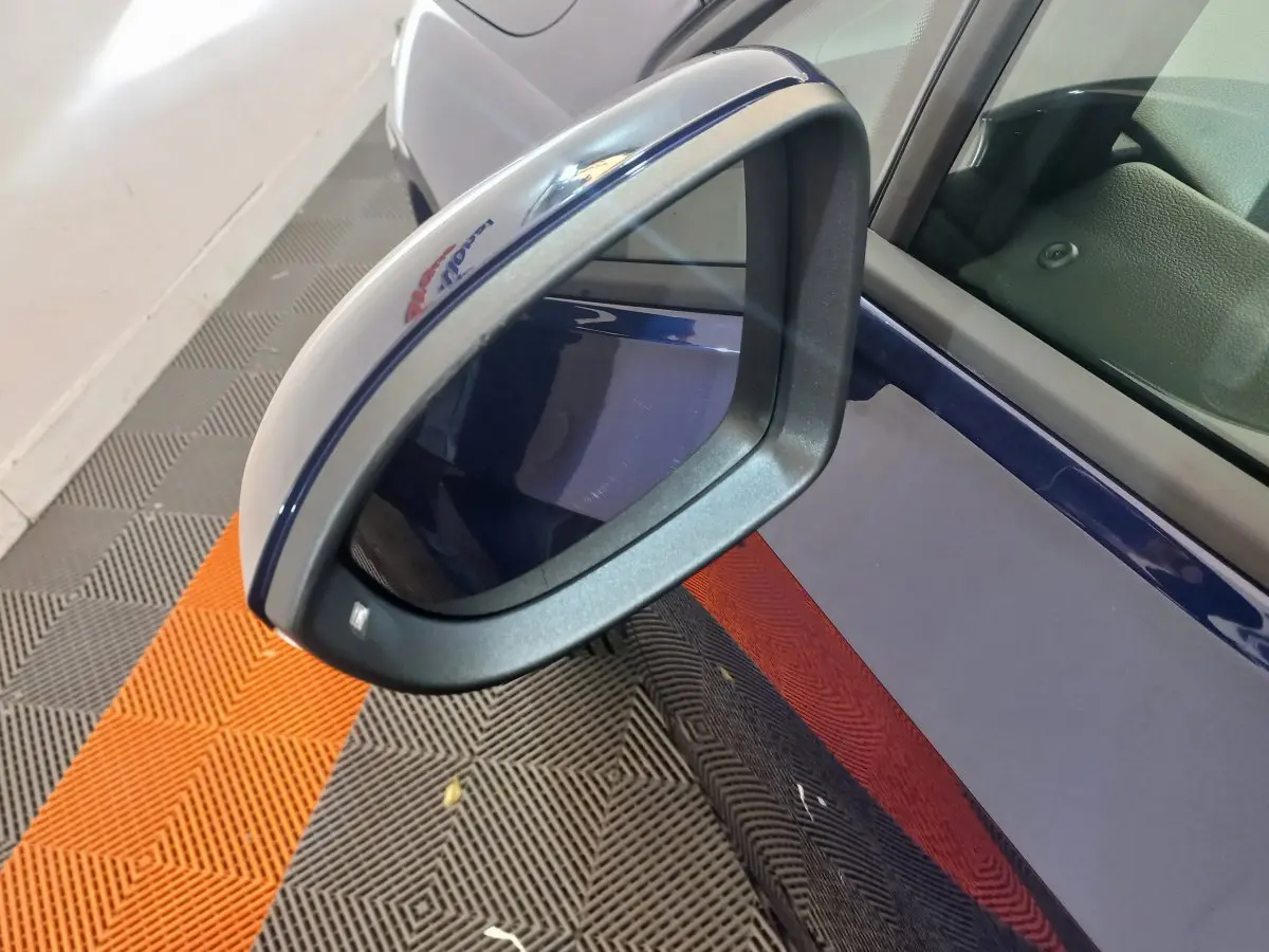 Gros plan sur le rétroviseur côté gauche bleu foncé de la Volkswagen Golf 2022 avec logo R-Line visible.