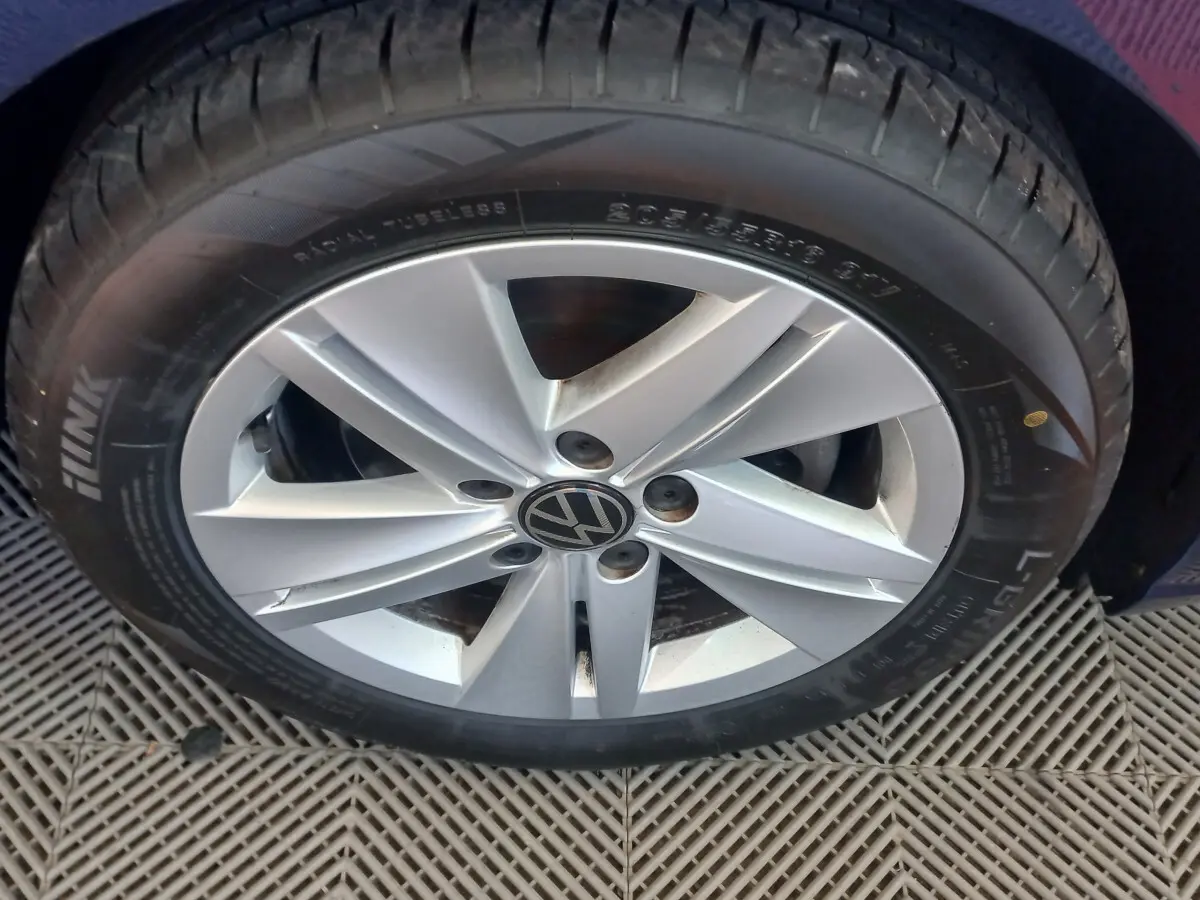 Gros plan sur la roue avant droite d'une Volkswagen Golf bleu, jante alliage argentée avec logo VW central.