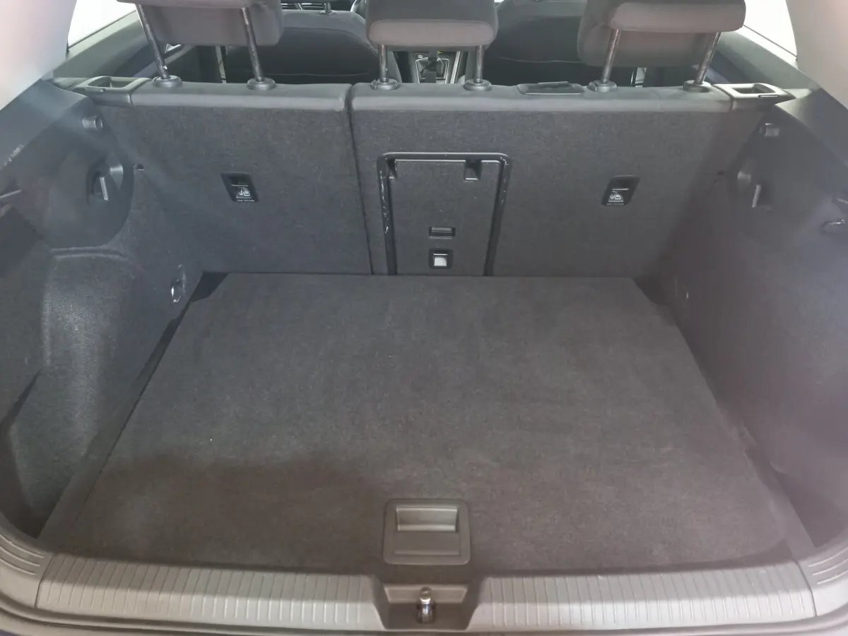 Vue intérieure du coffre noir de la Volkswagen Golf 1.5 ETSI 2022 avec banquette arrière rabattable et trappe centrale.