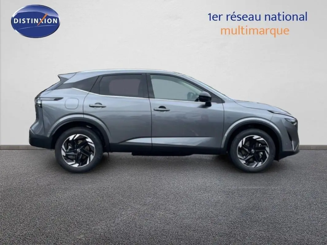 Vue de profil côté gauche du Nissan Qashqai gris 2025 avec jantes aluminium et barres de toit visibles.