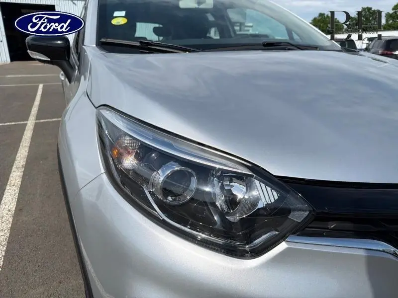 Gros plan sur le phare avant droit du Renault Captur gris platine, mettant en valeur la calandre et le rétroviseur noir.