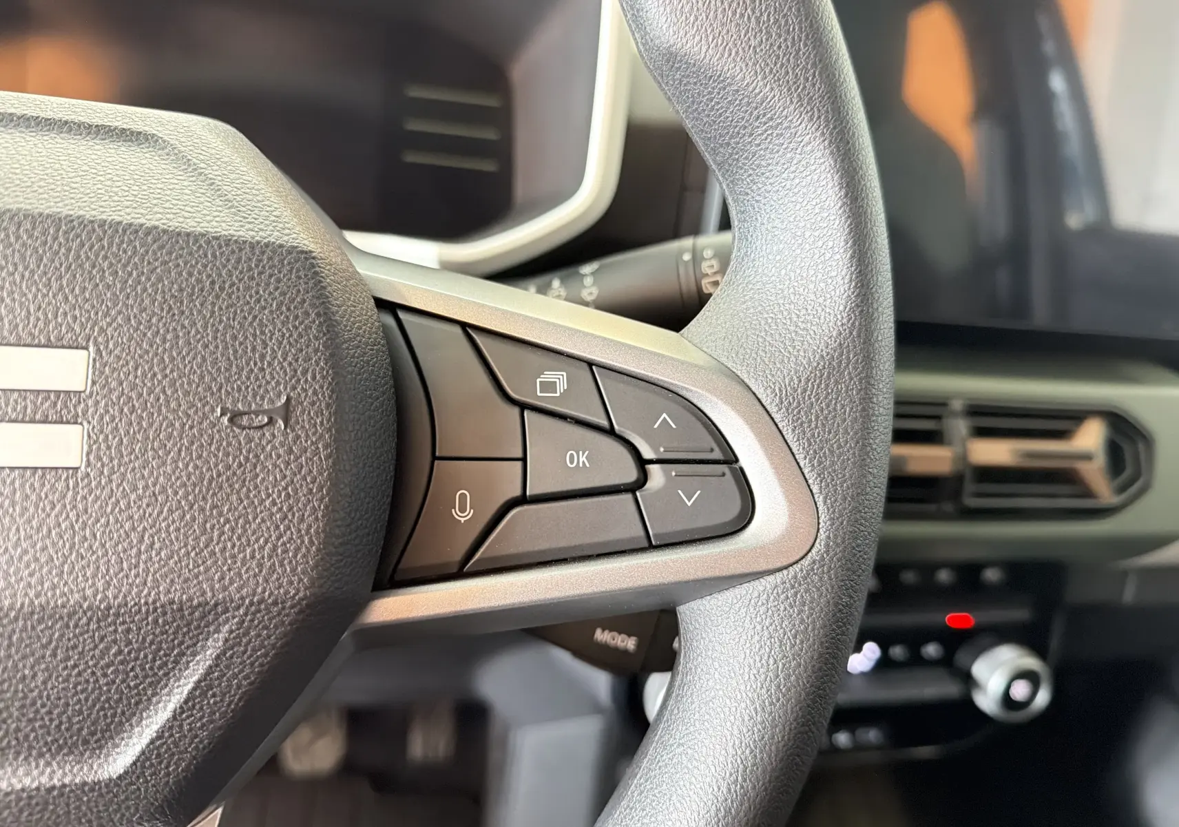 Gros plan sur le côté droit du volant du Dacia Spring 65 Extreme 2026, avec commandes multifonctions et tableau de bord partiel.