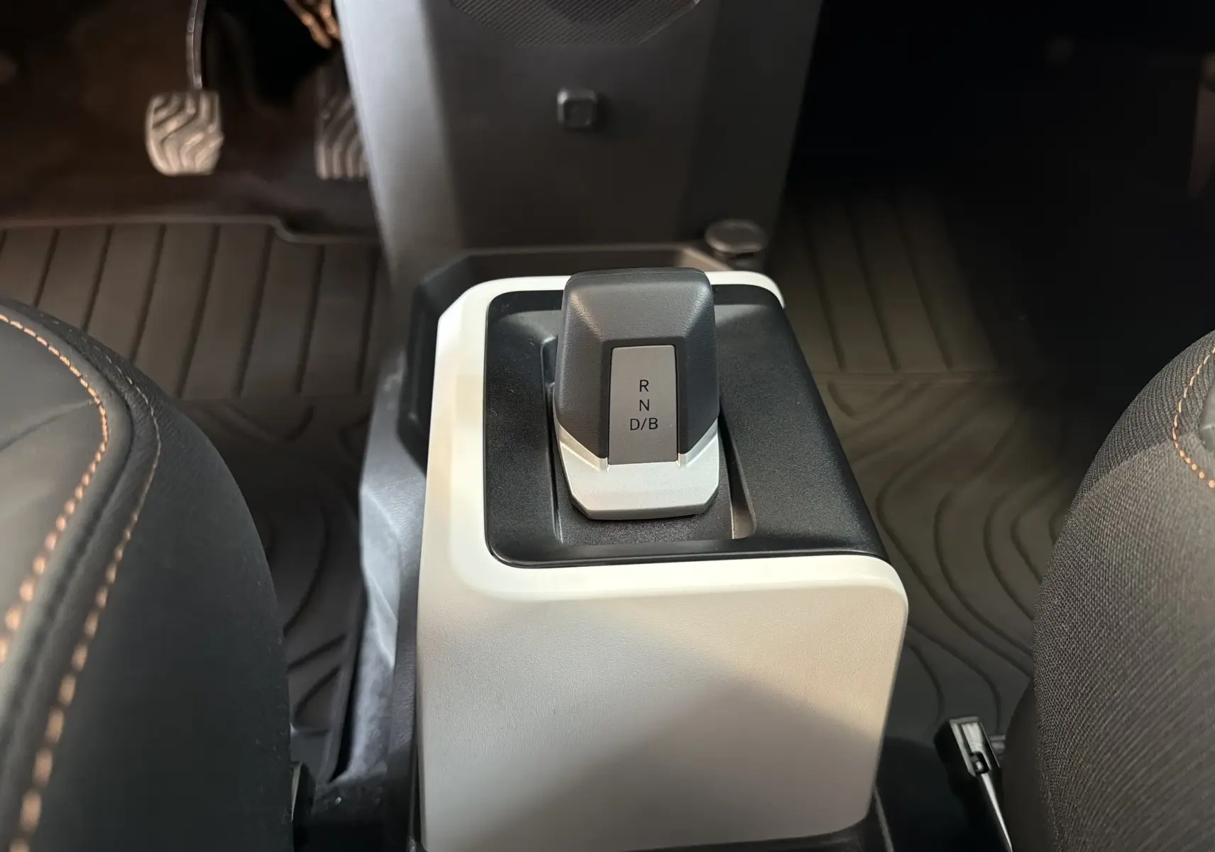 Gros plan sur le levier de vitesses automatique de la Dacia Spring 65 Extreme 2026, intérieur noir et beige avec surpiqûres orange.