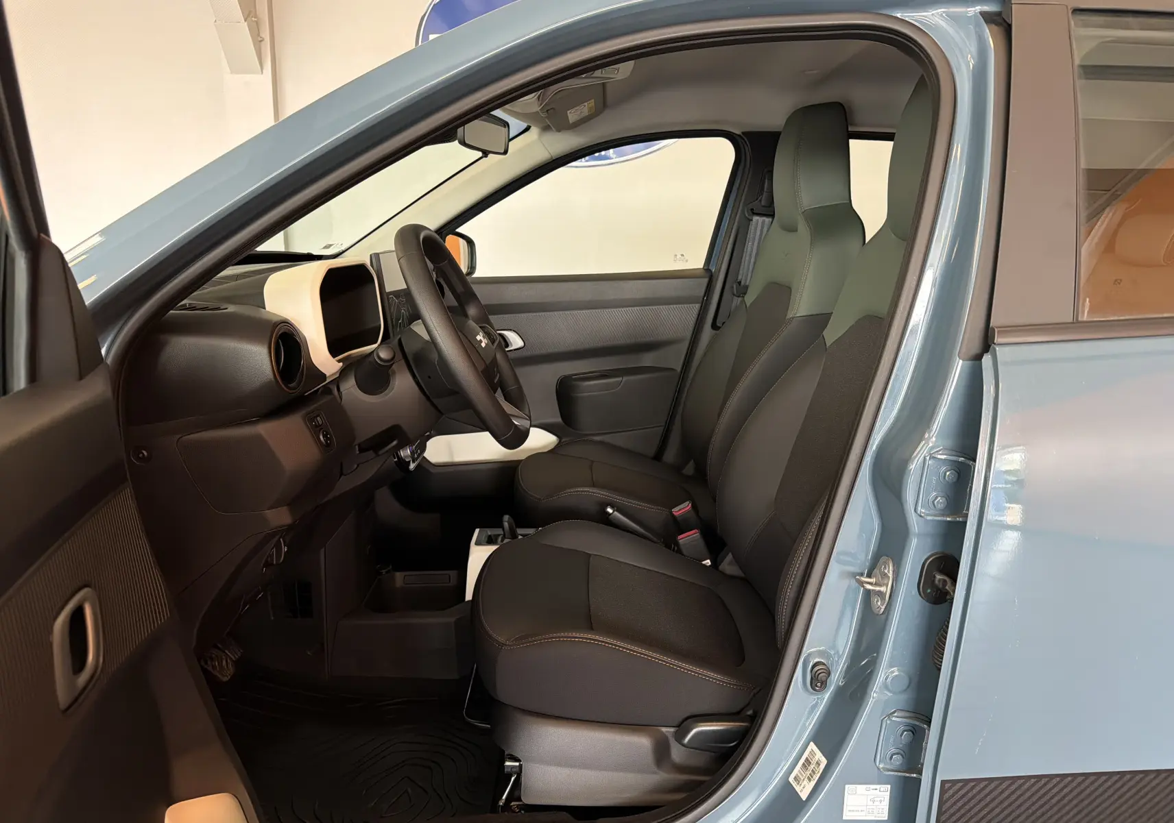 Vue intérieure côté conducteur de la Dacia Spring 65 Extreme 2026 bleu ardoise, avec sièges noirs et tableau de bord minimaliste.
