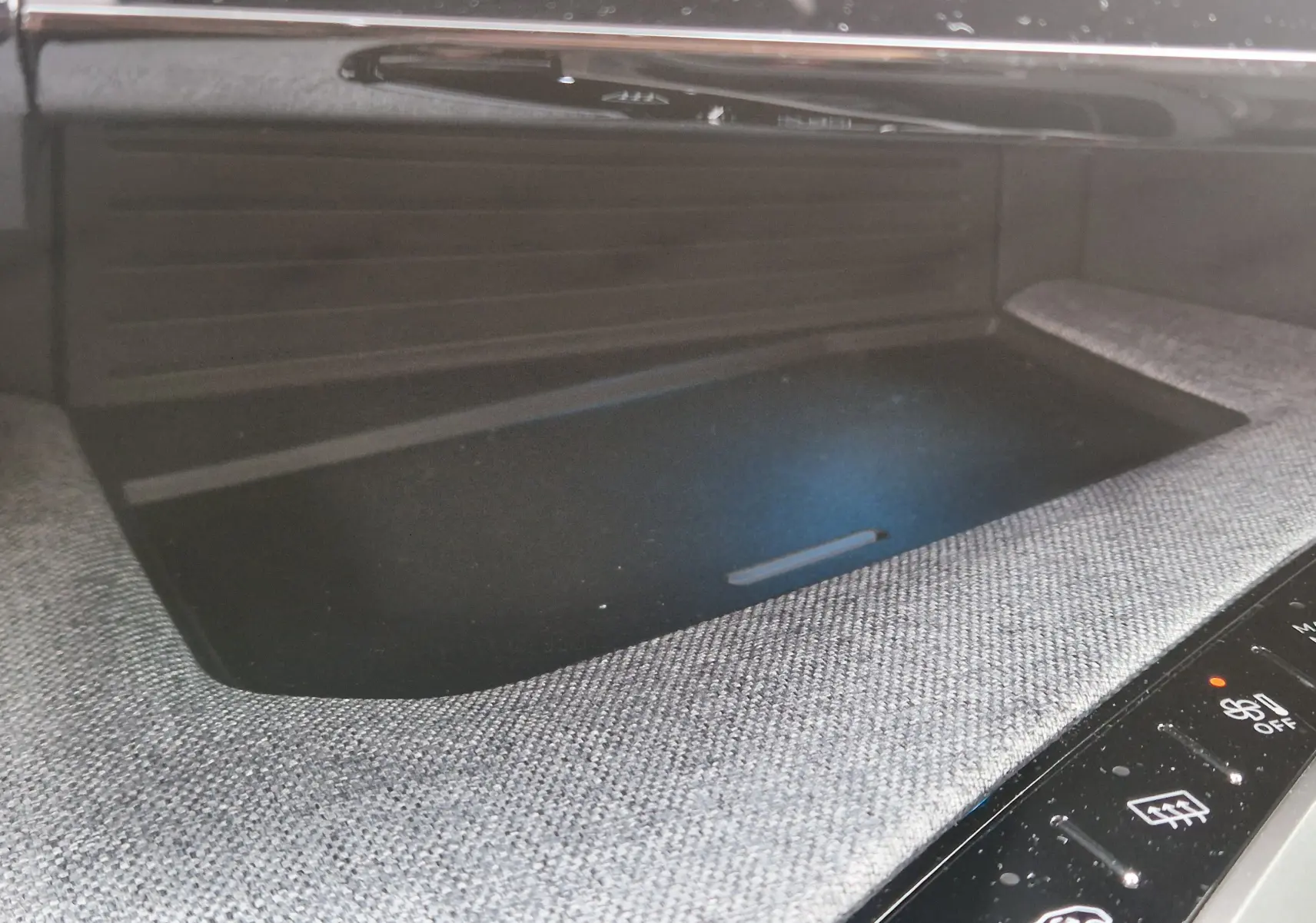 Détail du rangement central avec surface textile grise et commandes tactiles noires du Peugeot 3008 1.2 Hybrid 2025.