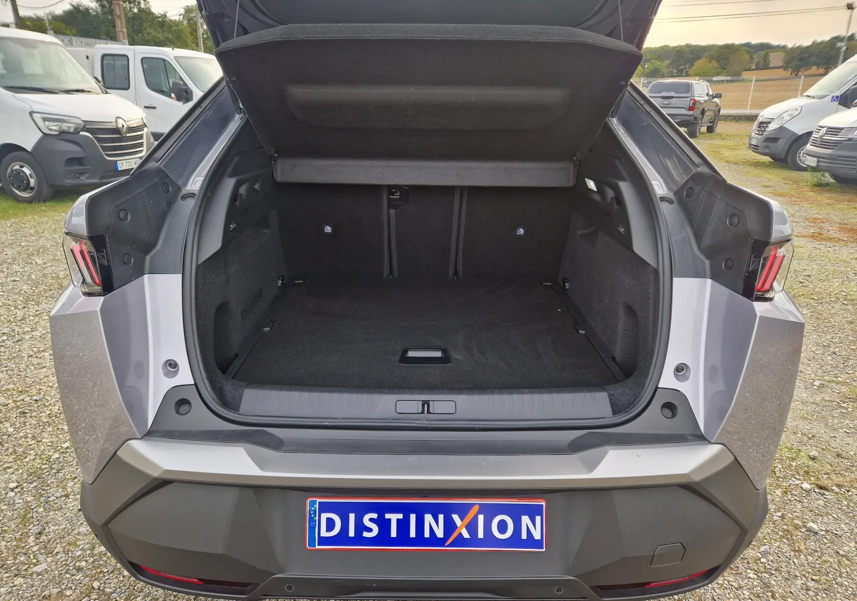 Coffre ouvert vu de l'arrière d'un Peugeot 3008 gris Artense 2025, soulignant l'espace de chargement vide.