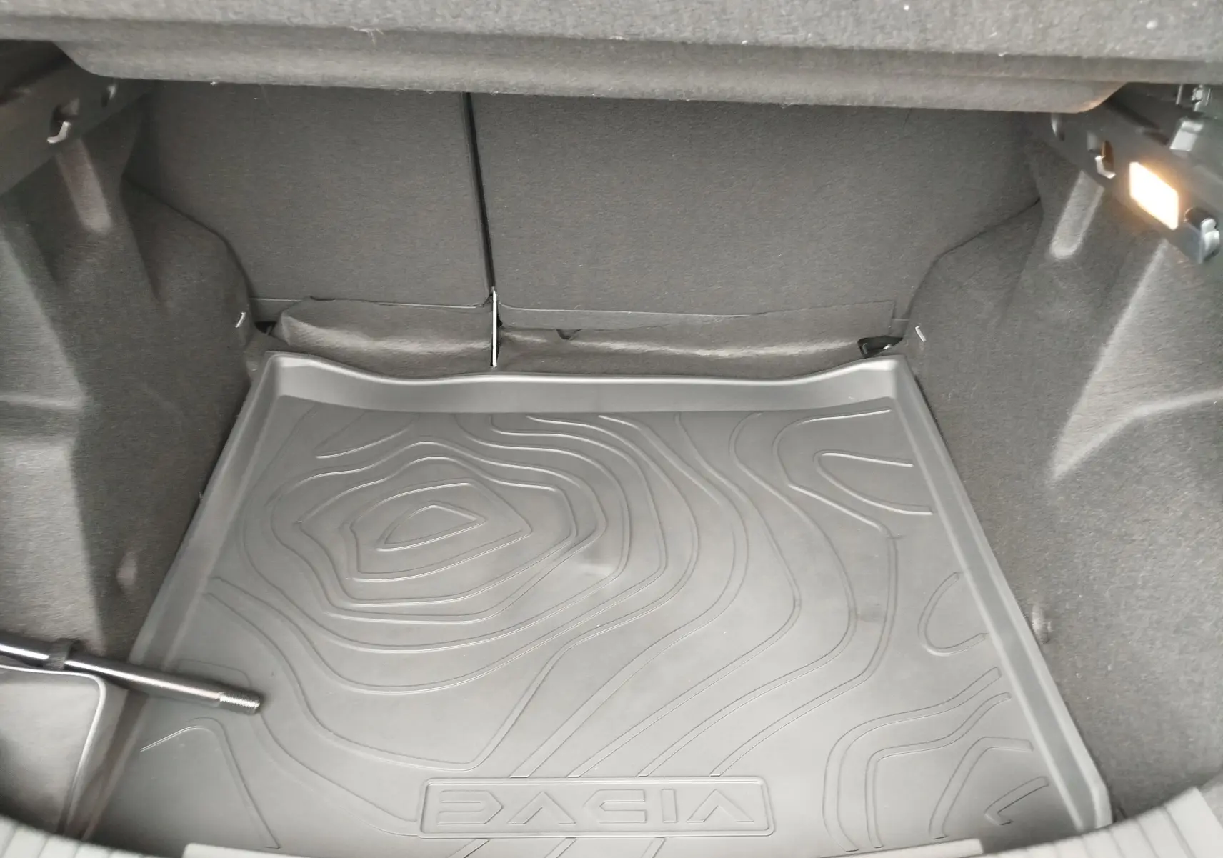 Coffre du Dacia Duster gris schiste 2025, vue intérieure montrant le tapis de sol avec logo DACIA embossé.