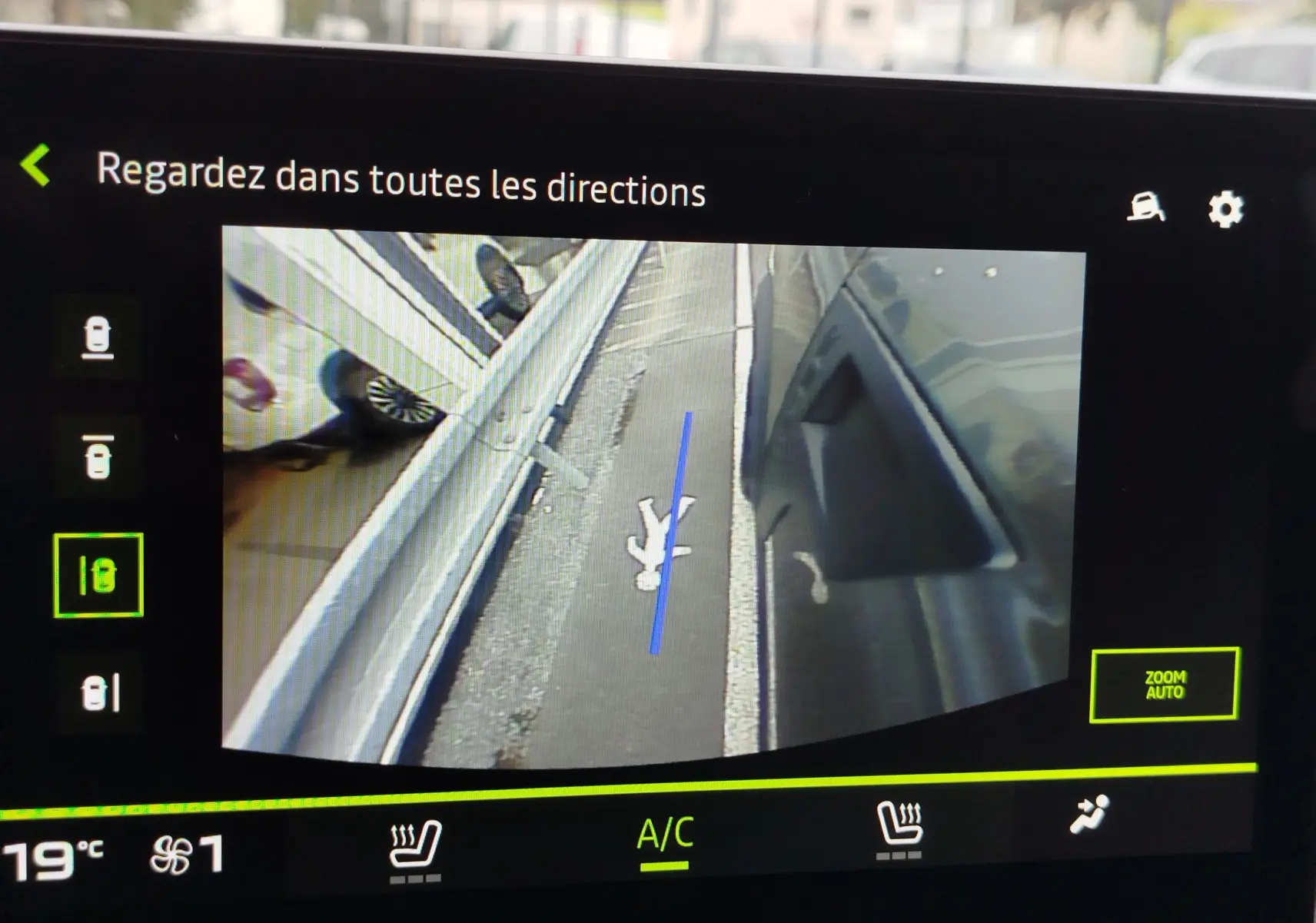 Vue caméra 360 du côté droit du Dacia Duster gris schiste, montrant le trottoir et une barrière métallique.