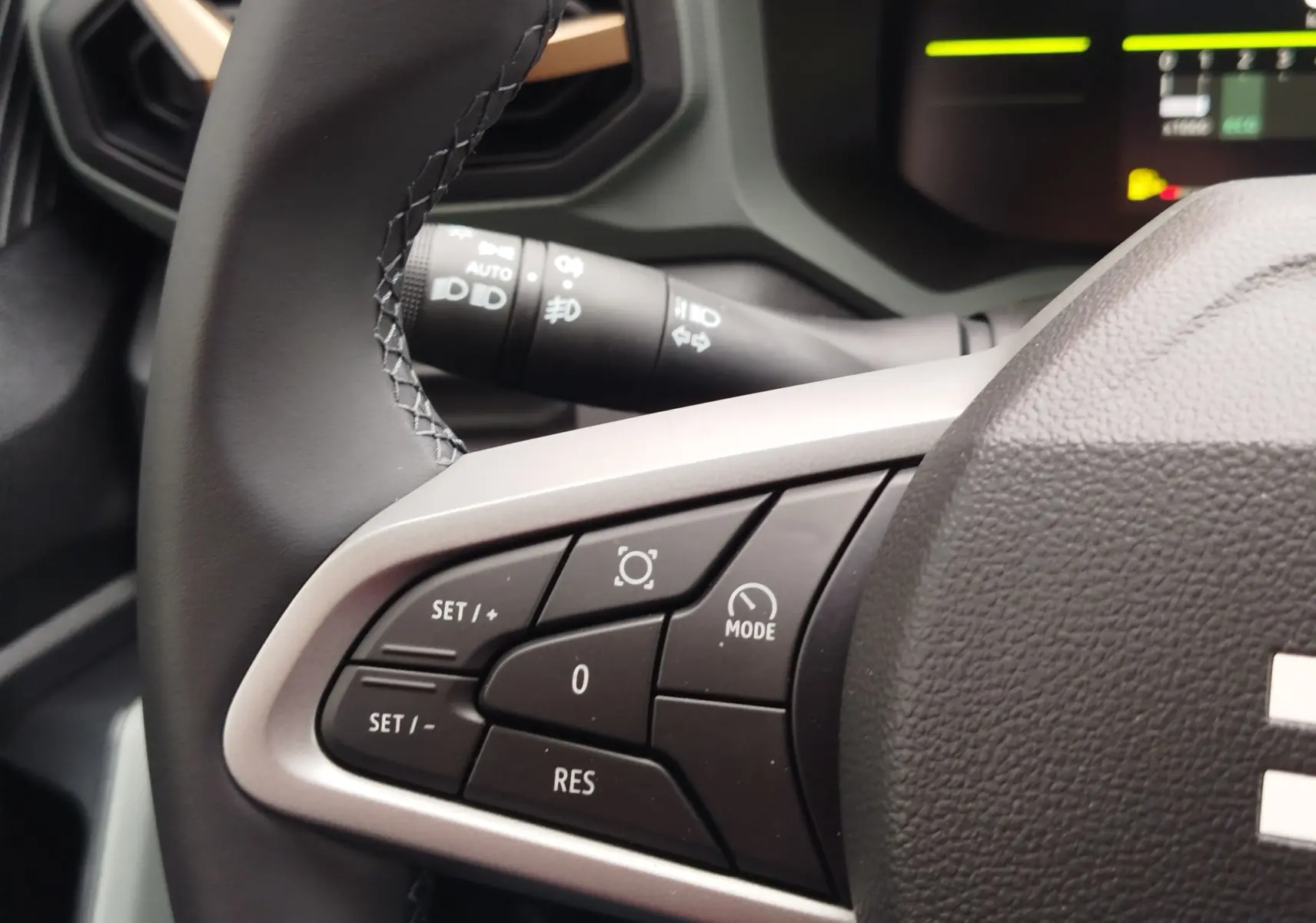 Gros plan sur les commandes au volant du Dacia Duster 2025, finition gris schiste, avec boutons de régulateur de vitesse.