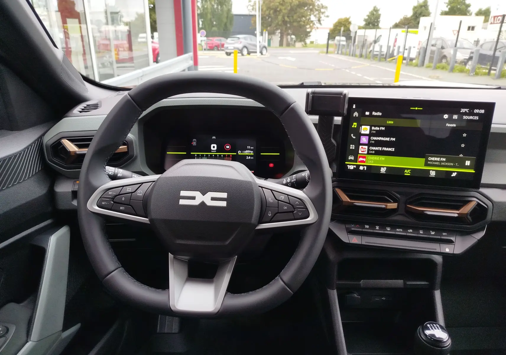 Vue intérieure du tableau de bord du Dacia Duster 2025, avec volant multifonction et écran tactile central allumé.