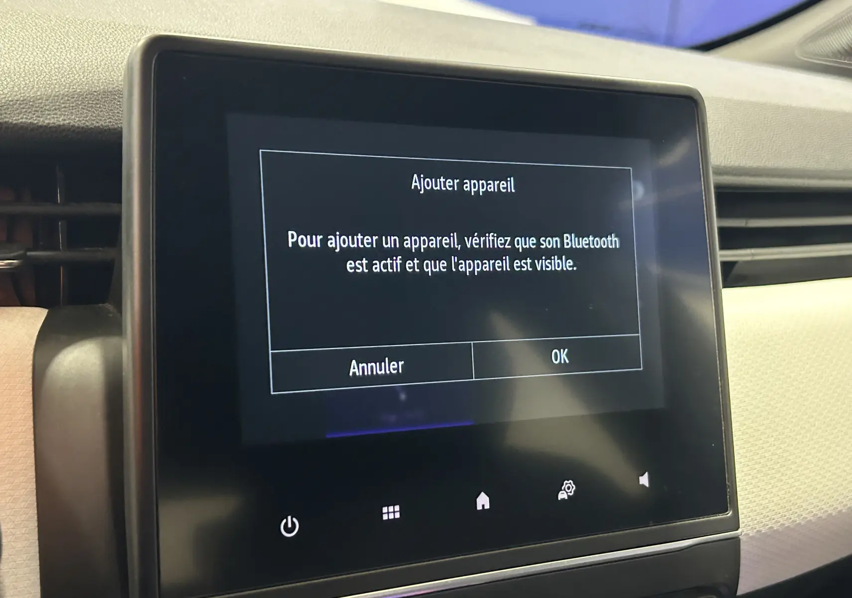 Écran tactile central affichant un message Bluetooth dans l'habitacle clair d'une Renault Clio V gris 2023.