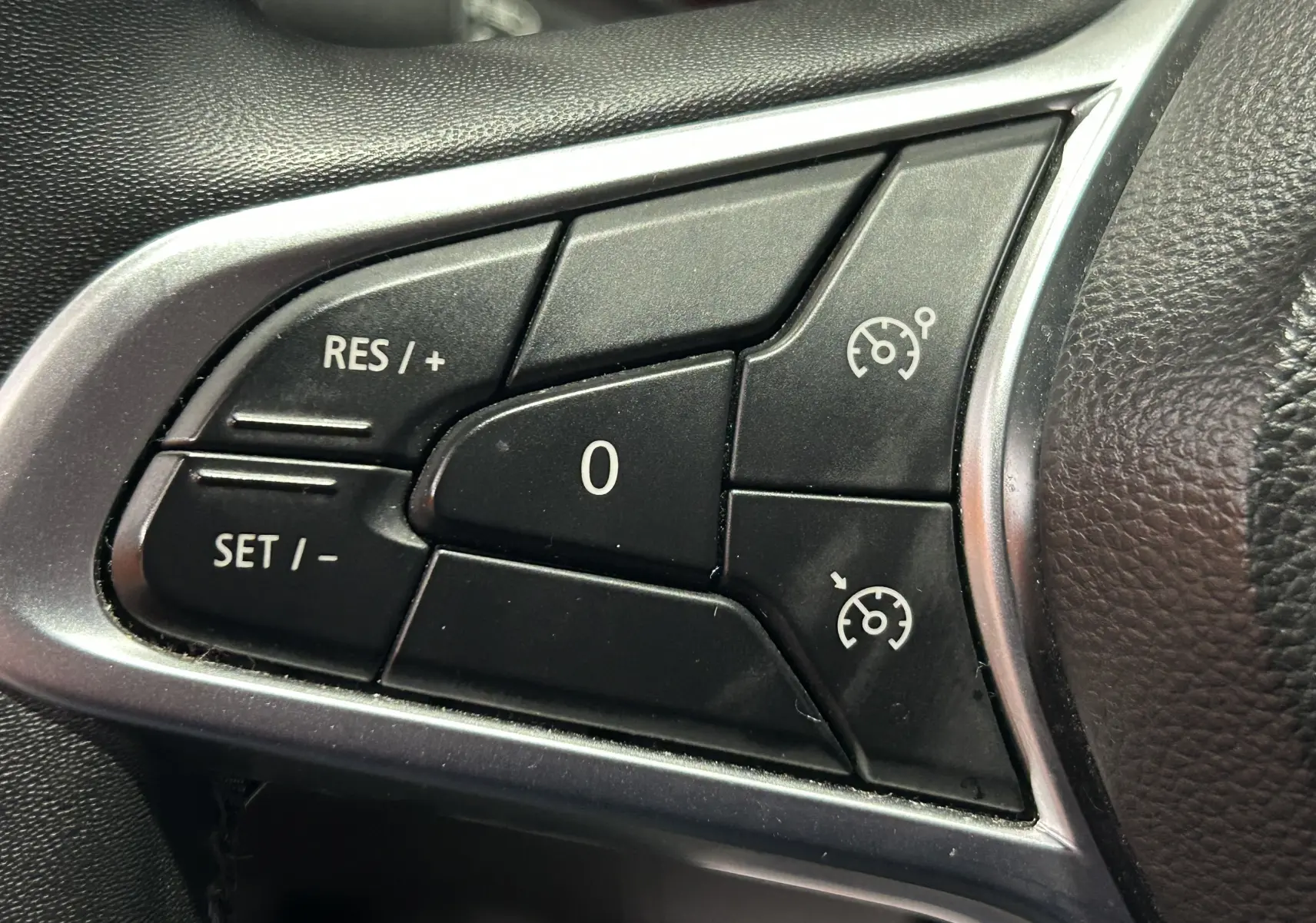 Gros plan sur les commandes de régulateur de vitesse au volant d'une Renault Clio V TCe 90 gris de 2023.