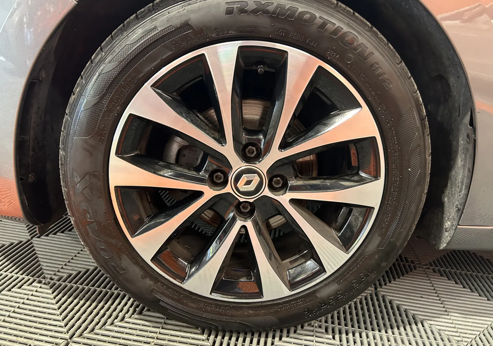 Gros plan sur la jante alliage bicolore d'une Renault Clio V gris 2023, mettant en valeur le logo central Renault.