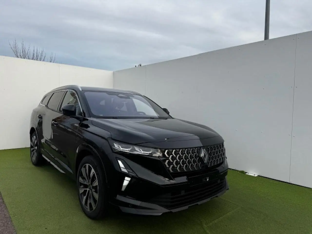 Renault Espace VI noir étoilé vu en 3/4 avant gauche, avec calandre gris chrome satin et jantes diamantées noires.