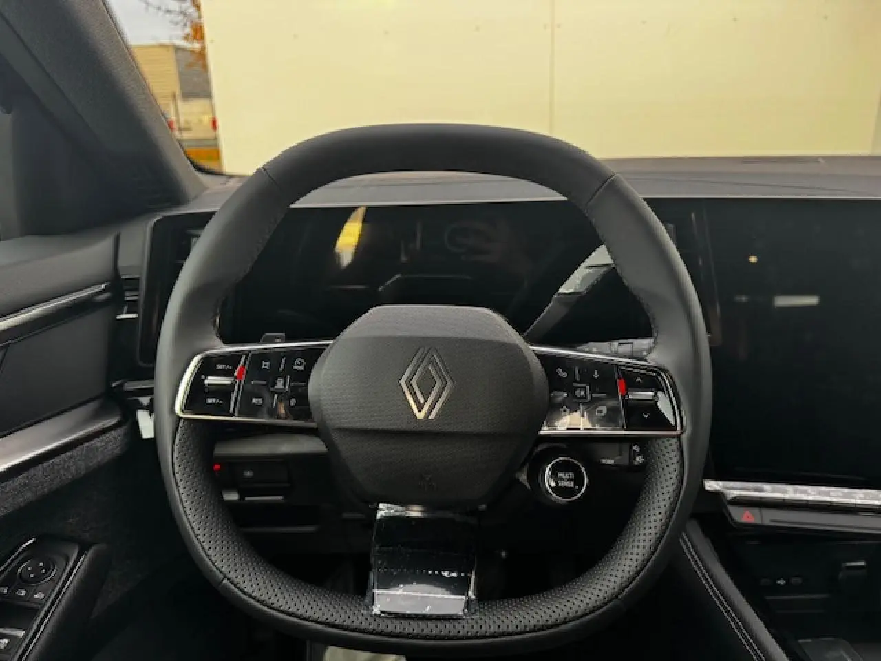 Volant rond noir avec logo Renault au centre, vue frontale du poste de conduite intérieur du Renault Espace VI hybride.