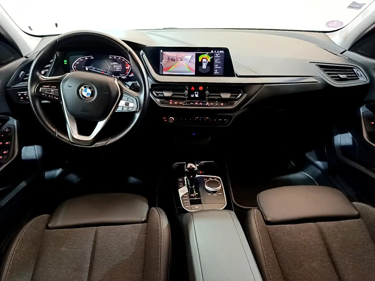 Intérieur BMW Série 1 118i 2021, vue frontale du tableau de bord avec écran central et volant multifonction cuir noir.