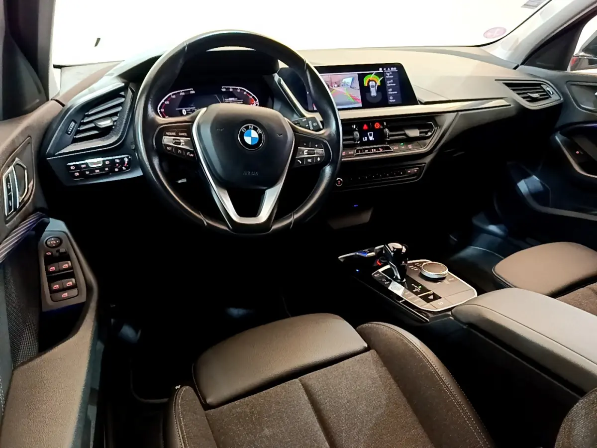 Intérieur de BMW Série 1 118i 2021, vue avant centrée sur volant cuir, tableau de bord digital et console moderne.