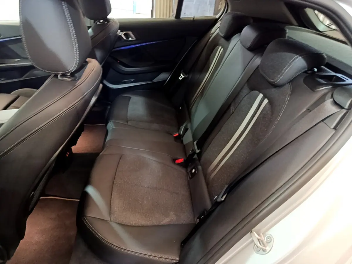 Vue intérieure côté droit sur la banquette arrière noire avec surpiqûres claires d'une BMW Série 1 gris clair 2021.