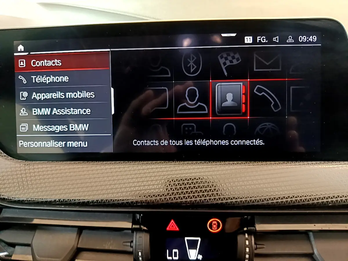 Écran central tactile de la BMW Série 1 2021 affichant le menu contacts avec tableau de bord beige texturé.