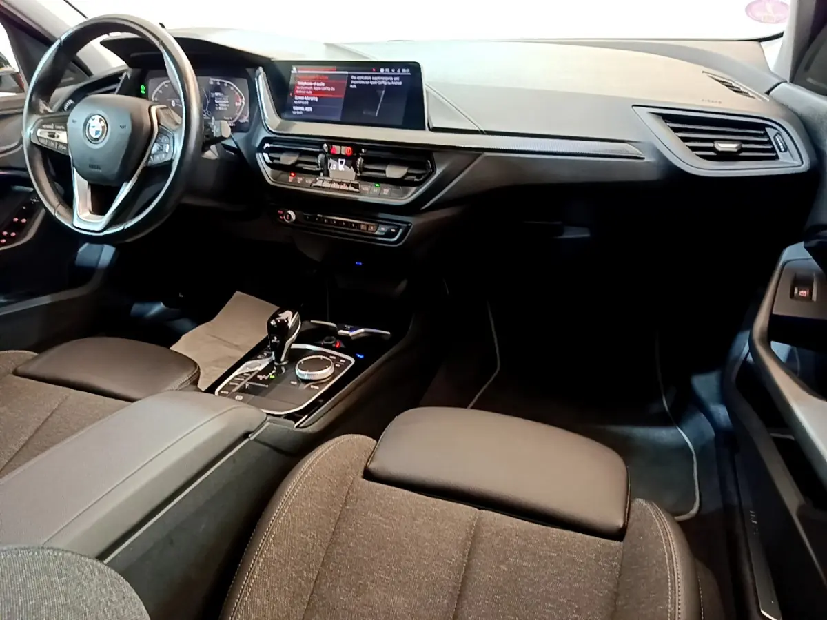 Intérieur de BMW Série 1 gris clair, vue côté conducteur sur tableau de bord, volant cuir et écran central tactile.