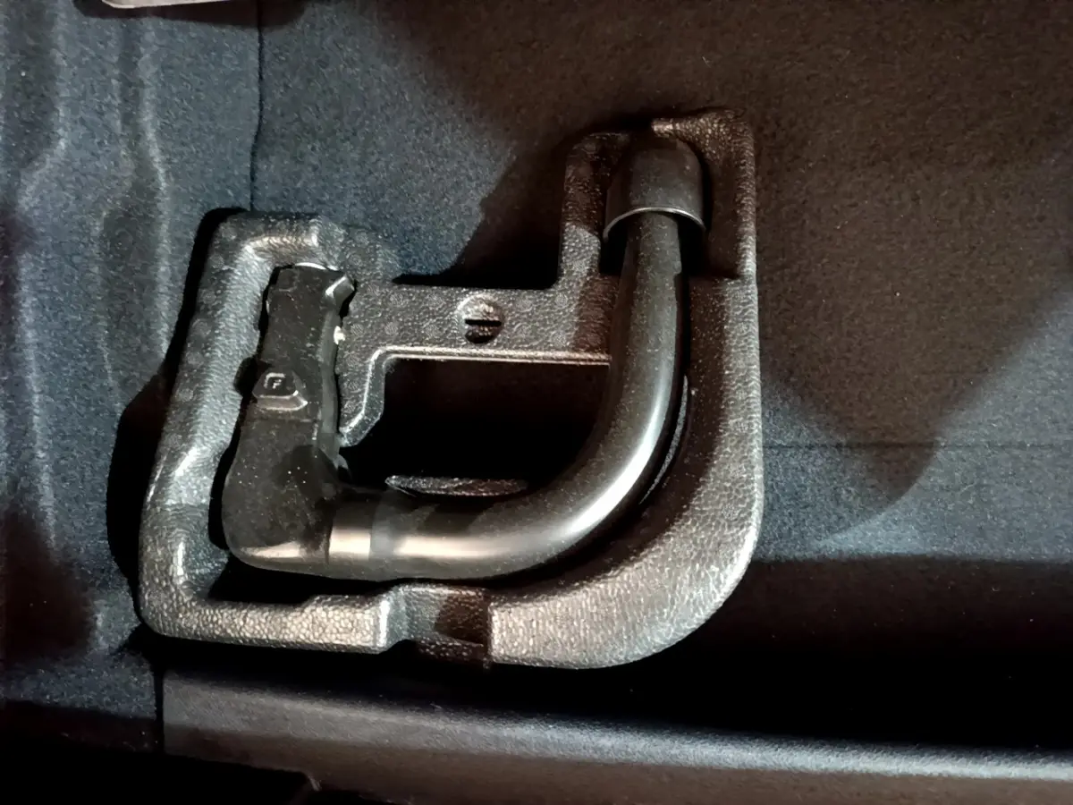 Gros plan sur l'attelage amovible noir logé dans le coffre d'une BMW Série 1 gris clair.