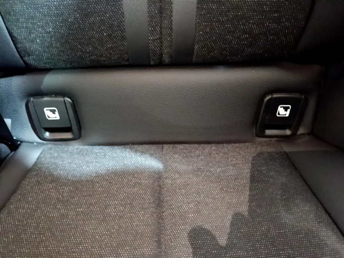 Gros plan sur les commandes de rabattement des sièges arrière en tissu gris foncé d'une BMW Série 1 Edition Sport 2021.